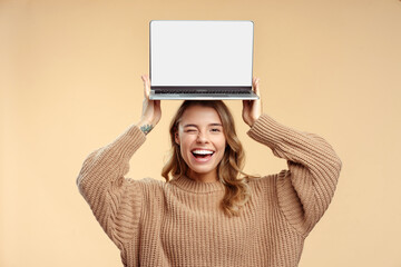 Happy student winks, holding laptop  on head showing computer screen, learning language, mockup....