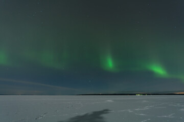 Green aurora borealis over the frozen and snowy lake in Tampere, Finland