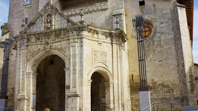 Tourist woman strolling through the main square and looking at the church in the Basque village of Salvatierra, Spain.