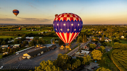 An Aerial View of Multiple Hot Air Balloons Floating Up During a Morning Launch on a Sunny Summer...