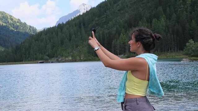 A young woman takes beautiful photos of mountains and forests on her phone 