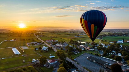 An Aerial View of a Multi-Colored Hot Air Balloon, Floating Over Pennsylvania Farmlands at Sunrise,...
