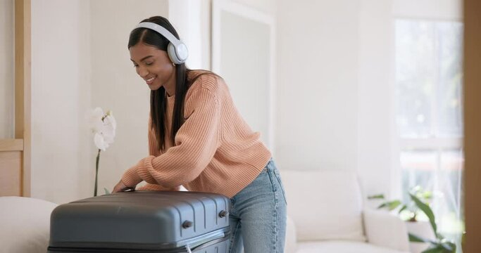Headphones, smile and woman packing luggage in home bedroom for travel, holiday journey or vacation preparation. Music, happy and Indian person with suitcase in apartment, listening to radio or audio