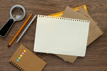 pencils magnifying glass torn paper - top view. Top view with copy space, flat lay.