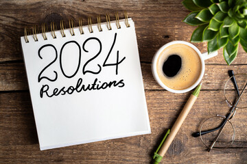 2024 New year resolutions on desk. 2024 goals list with notebook, coffee cup, plant on wooden...