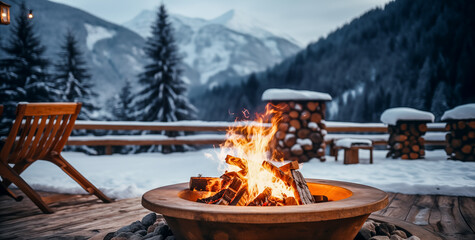 Outdoor fireplace Fire Pit in a snowy setting on a restaurant terrace in the mountains in a ski resort. Winter Holiday and travel concept. - obrazy, fototapety, plakaty