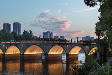 the light shines on the arches of an arched bridge at sunset