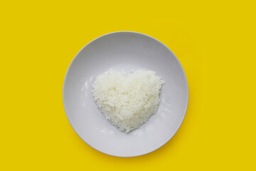 Cooked white rice in white plate on yellow background.