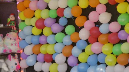 This video shows a dart hitting a balloon at a carnival game in slow motion. - Powered by Adobe