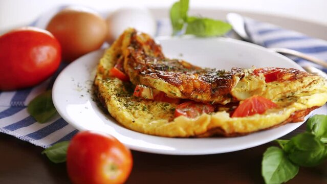 Stuffed omelette with tomatoes on a light wooden background.