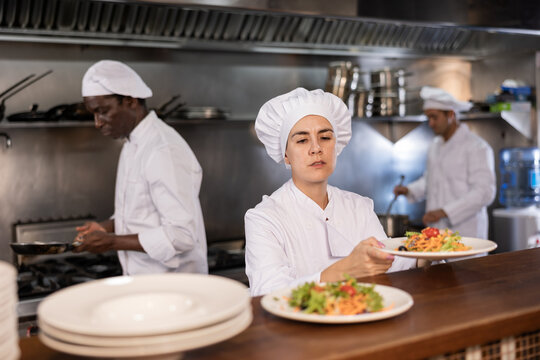 Female chef puts ready meals on shelves in restaurant