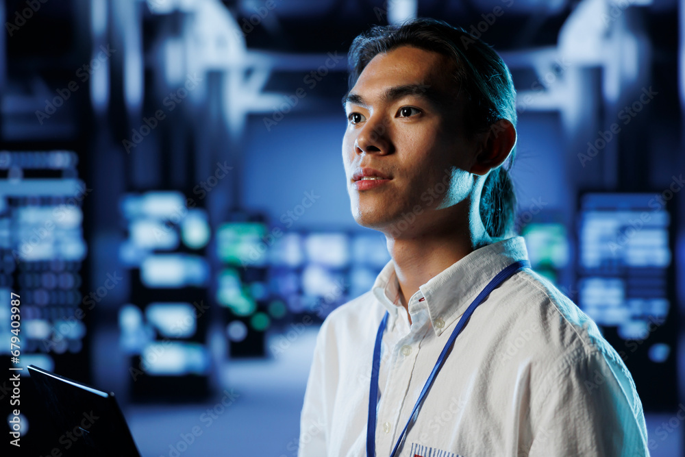 Poster certified technician in data center uses laptop to prevent system overload during peak traffic perio