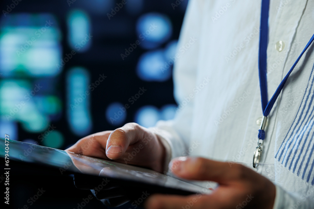 Poster engineer in data center using tablet to prevent system overload, close up. employee in server room e
