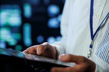 Engineer in data center using tablet to prevent system overload, close up. Employee in server room ensuring there is enough network connectivity for smooth operations, blurry background
