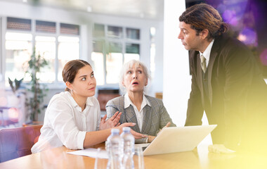 Fototapeta premium Adult man, elderly woman and young woman in business clothes having meeting in office