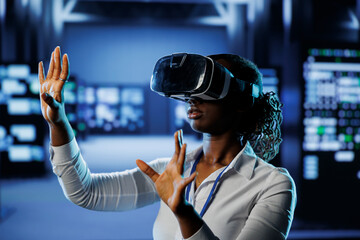 Trained technician in data center uses virtual reality to prevent system overload. Experienced VR headset user in server room ensuring enough network bandwidth for smooth operations