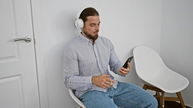 Young hispanic man having video call sitting on chair smiling at waiting room