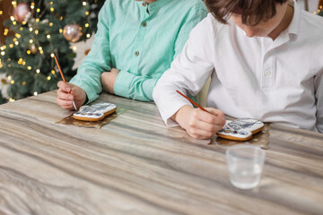 Children draws food paints on Christmas homemade gingerbread cookies. Christmas concept. Close up.