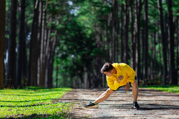 Trail runner is stretching for warm up outdoor in the pine forest dirt road for exercise and...