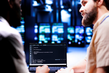 Colleagues updating server clusters, writing complex binary code scripts on laptop terminal. Admins...
