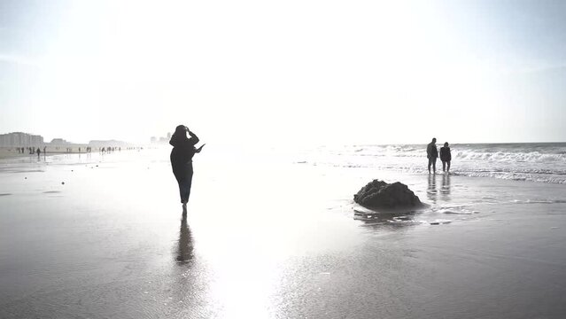 a girl in a coat walks on the beach