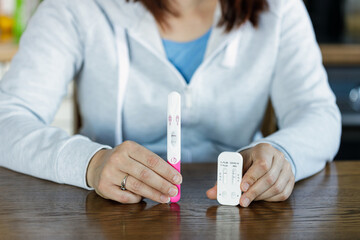 Woman holding positive pregnancy test and positive COVID test. Pregnant woman being sick cannot use...