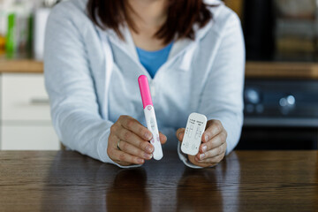 Woman holding positive pregnancy test and positive COVID test. Pregnant woman being sick cannot use...