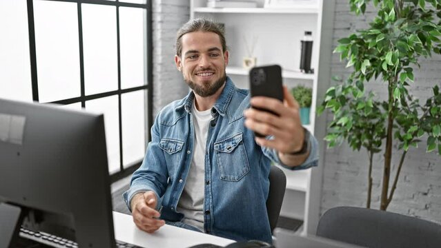 Young hispanic man business worker make selfie by smartphone smiling at the office
