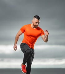 Runner on the training outdoor. Athletic man doing fitness exercises on the ocean beach. Triathlon...