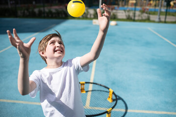 child playing sports game spikeball, spikeball. the boy is hitting the yellow ball in a miniature...