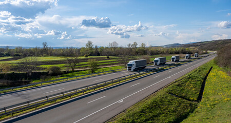 Caravan or convoy of trucks in line on a country highway. A convoy of trucks (lorries) heading down...