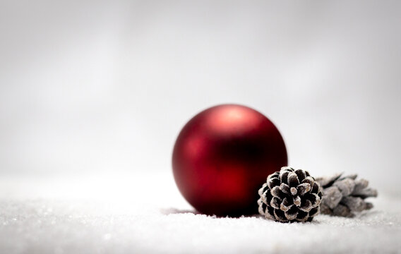Red bauble with snowy pine cones on a white background