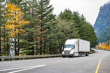 Professional long hauler big rig white semi truck transporting cargo in refrigerator semi trailer...