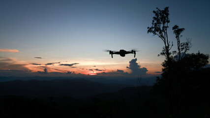 Fototapeta na wymiar Silhouette drone at top mountain against sunset sky