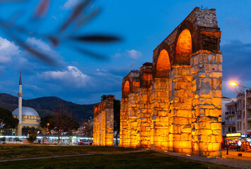 View of lighted partially preserved Byzantine aqueduct in center of Turkish town of Selcuk at dusk - obrazy, fototapety, plakaty
