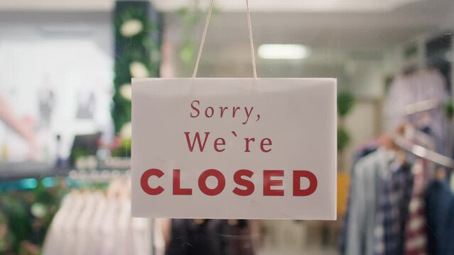 Trendy clothing store being closed at night after finished working hours. Extreme close up shot on sorry we are closed message sign on fashion boutique door in mall at shift end