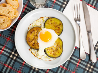 Delicious fried eggs, cooked with sliced and fried eggplant, served with bread