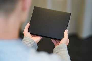 top view of an black voucher gift box as mockup for black friday offers holding with hands of a man - obrazy, fototapety, plakaty
