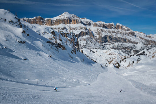View of a ski resort piste with people skiing in Dolomites in Italy. Ski area Arabba. Arabba, Italy