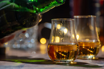 Pouring in Speyside whisky glass of whisky, single malt and blended scotch whisky served in bar in Edinburgh, Scotland, UK with party lights on background