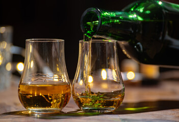 Pouring in Speyside whisky glasses of whisky, single malt and blended scotch whisky served in bar in Edinburgh, Scotland, UK with party lights on background