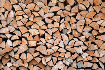 Firewood stacked near the wooden wall of old hut. Many chopped logs of firewood close up