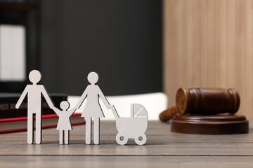 Family law. Figure of parents with children, books and gavel on wooden table, space for text