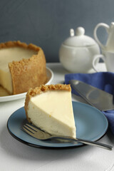 Piece of tasty vegan tofu cheesecake and fork on white table