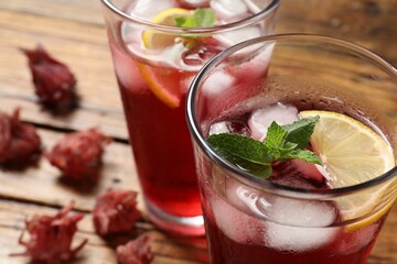 Glass of delicious iced hibiscus tea on wooden table, closeup. Space for text