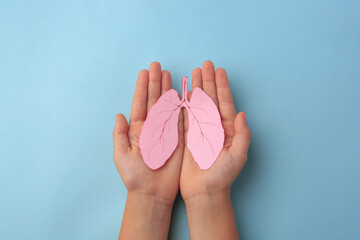 Child holding paper human lungs on light blue background, top view - obrazy, fototapety, plakaty