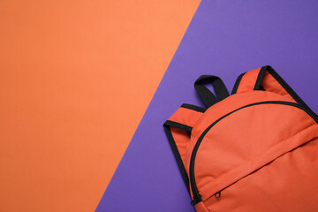 Stylish orange backpack on color background, top view. Space for text