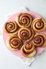 Many tasty cinnamon rolls on white table, top view