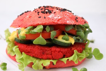 Tasty pink vegan burger with vegetables, patty and microgreens on white background, closeup