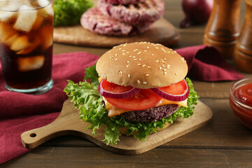 Tasty vegetarian burger with beet patty, sauce and soda drink on wooden table